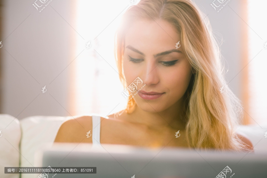 金发女人在客厅里使用笔记本电脑