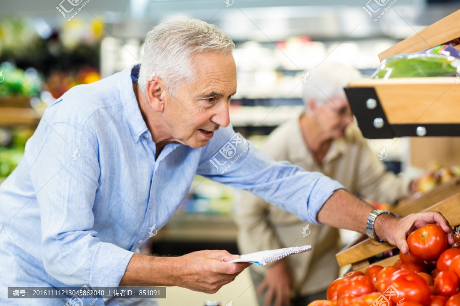 在超市里选购蔬菜的老人