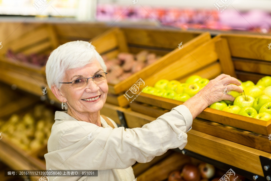 在超市里挑选苹果的老太太