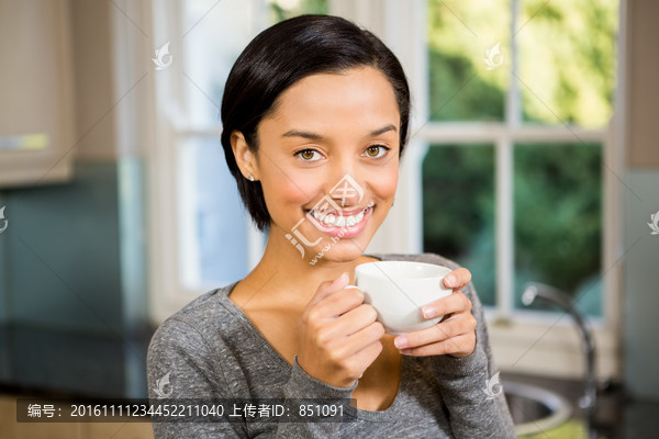 微笑的女人在喝一杯咖啡