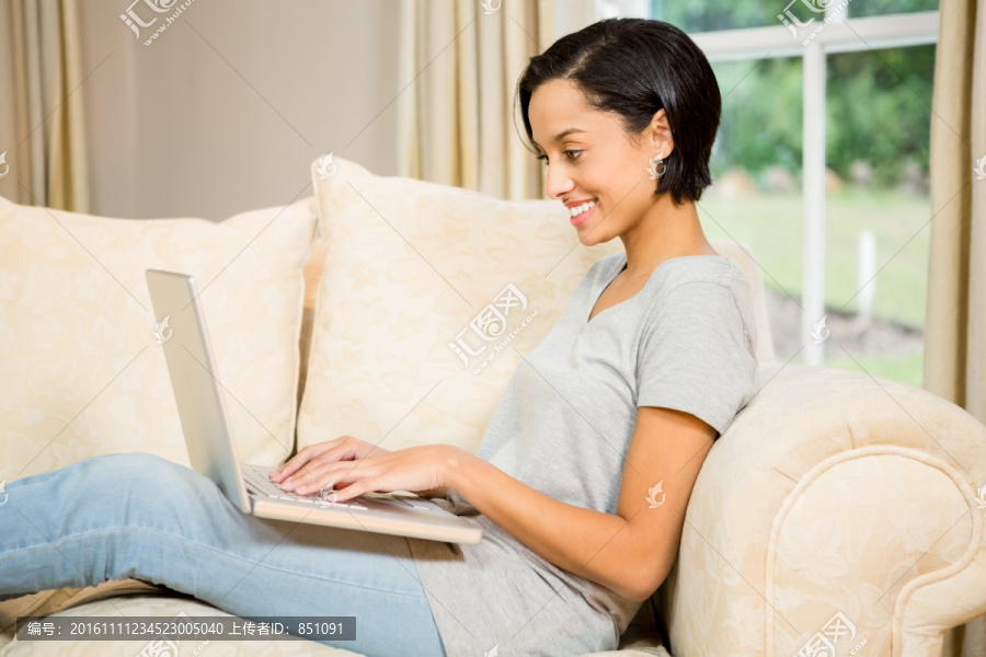 坐在沙发上使用笔记本电脑的女人