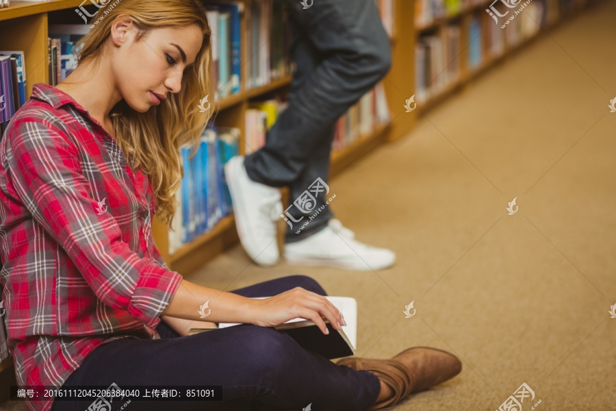 坐在图书馆地板上看书的大学生