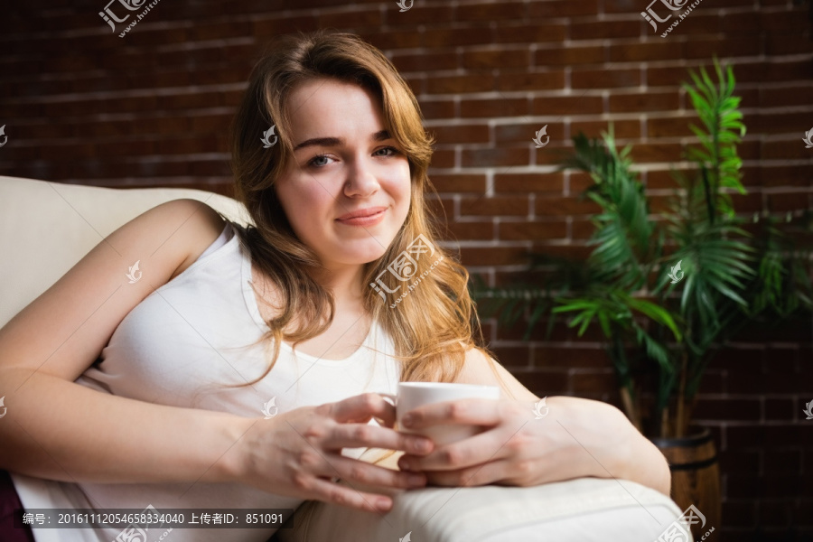 坐在沙发上喝咖啡的女人