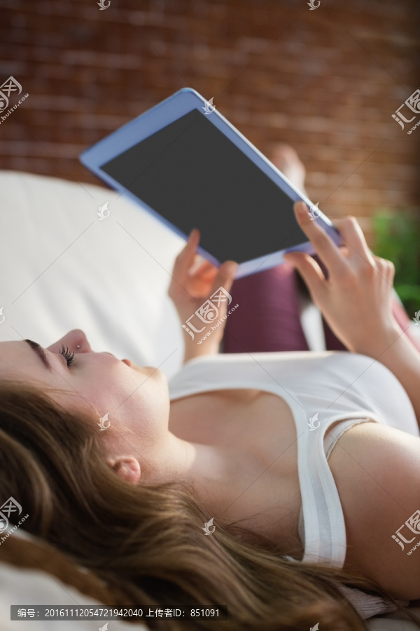 女人躺在沙发上使用平板电脑