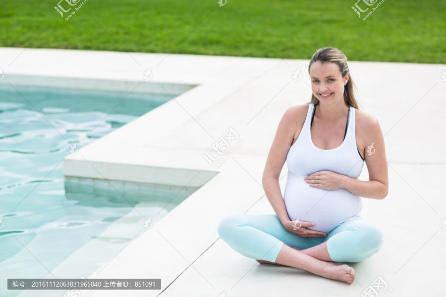坐在泳池邊撫摸肚子的孕婦