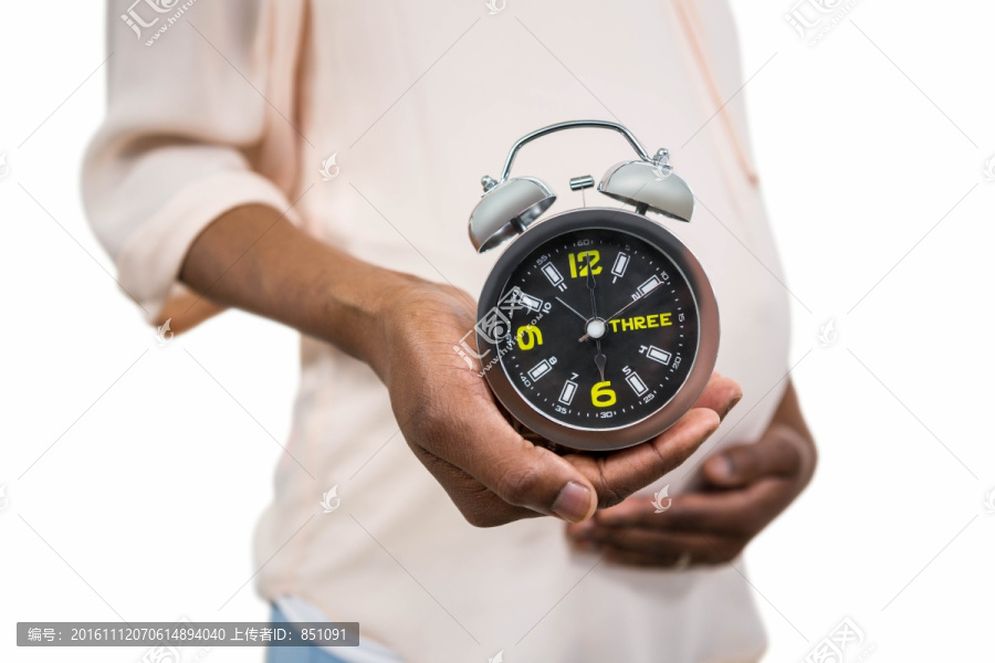 怀孕的女人拿着一个闹钟