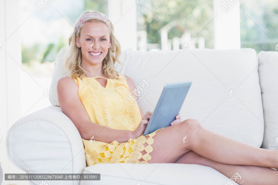 坐在沙发上使用平板电脑的女人