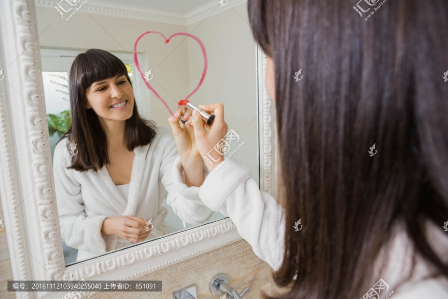 美丽的女人用口红在镜子上画爱心