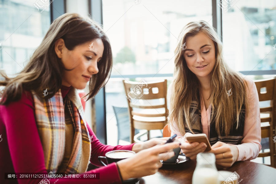 年轻女人和朋友在咖啡馆喝咖啡