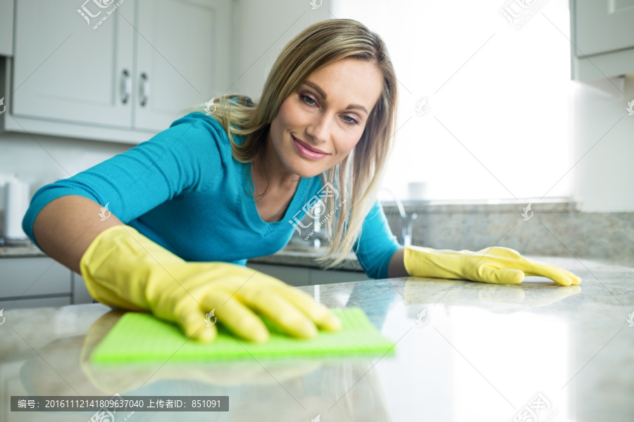 拿着海绵抹布擦厨房台面的女人
