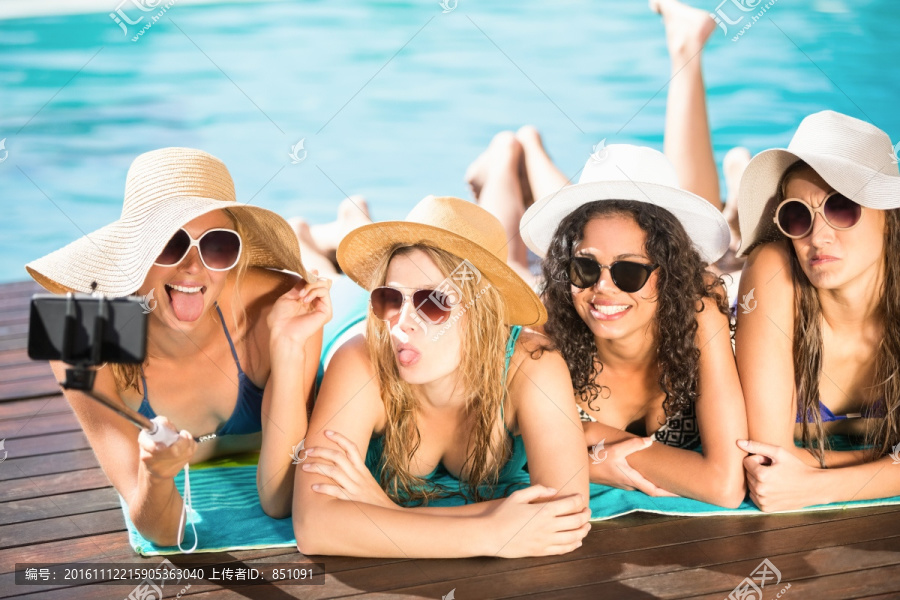 在泳池边拿着手机自拍的女人们