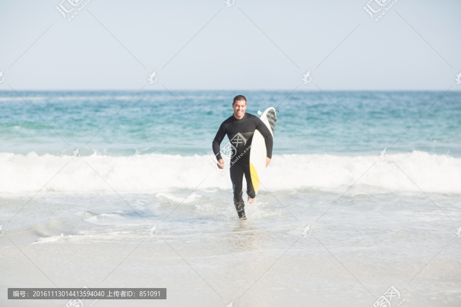 在海边拿着冲浪板的男人