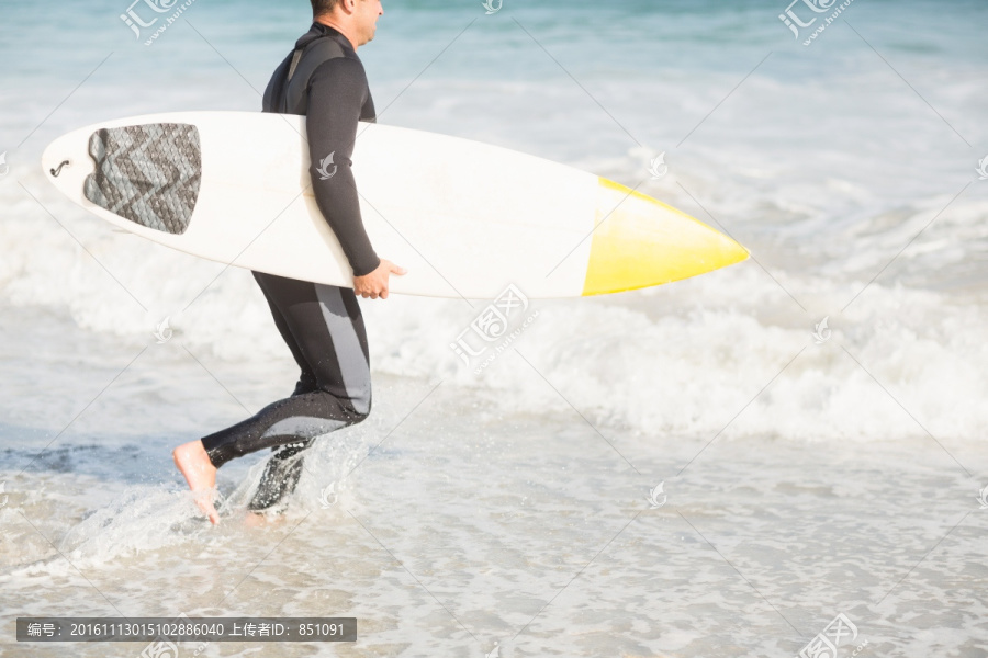 拿着冲浪板走向大海的男人