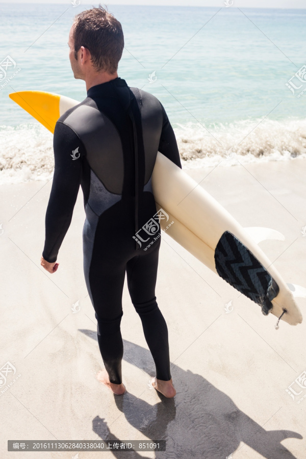 穿着潜水衣拿着冲浪板的男人