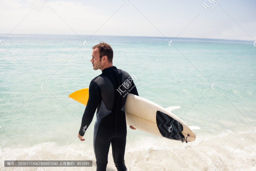 拿着冲浪板走向大海的男人