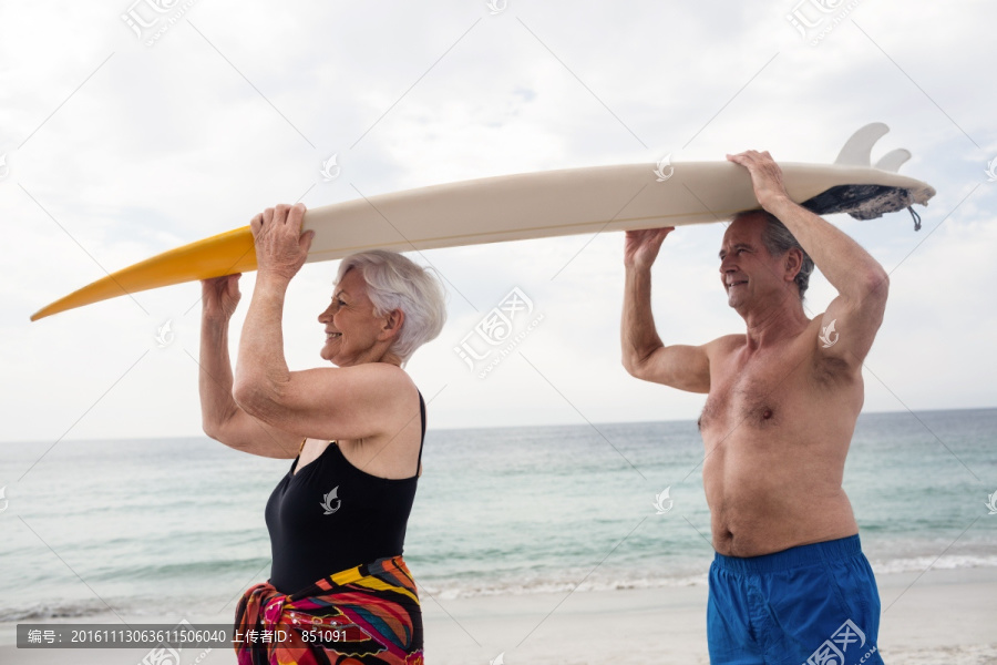 举着冲浪板放在头上的老夫妇