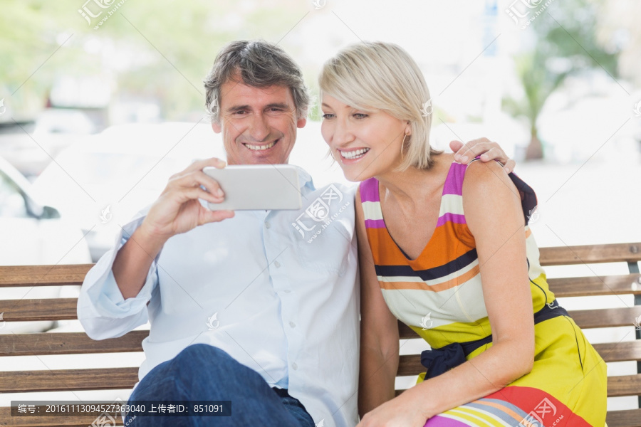 坐在公园长椅上用手机的夫妇