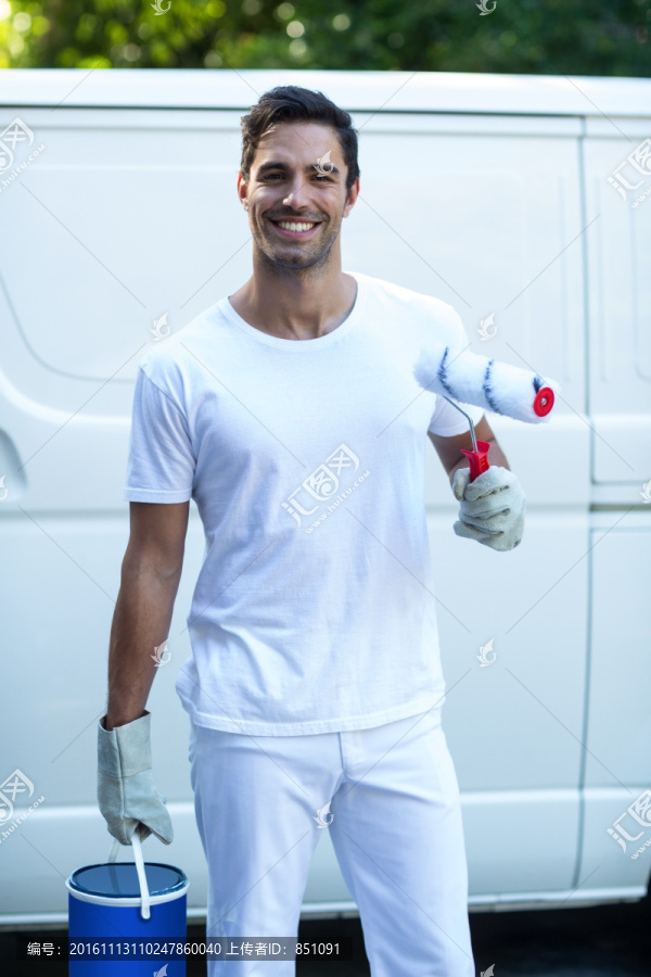 微笑的男人拿著油漆滾筒和水桶