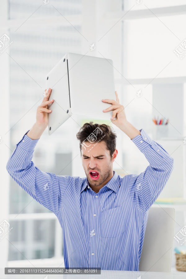 愤怒的举起笔记本电脑的男人