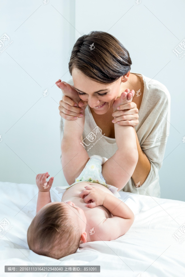 在卧室里逗弄小婴儿的母亲