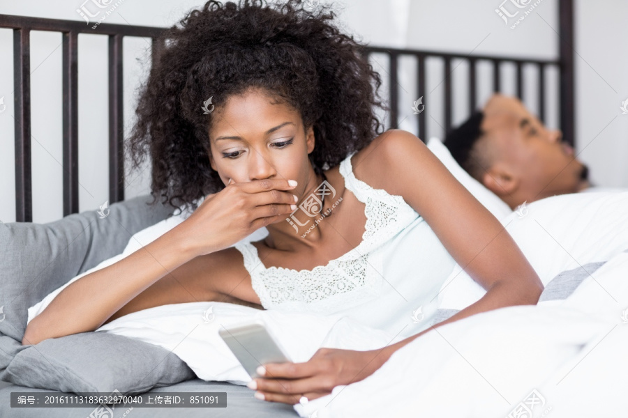 震惊的女人在床上看手机