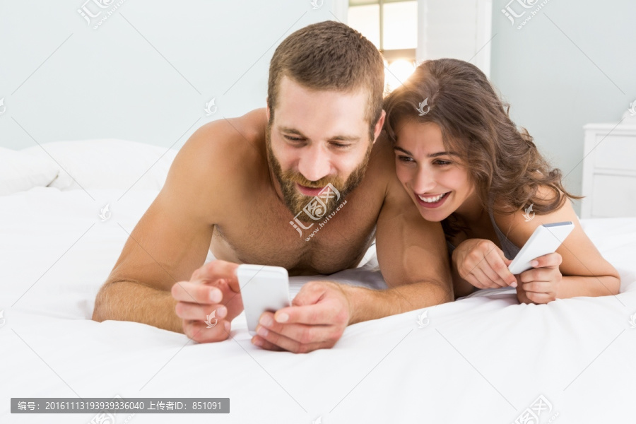 趴在床上看手机的一对夫妇
