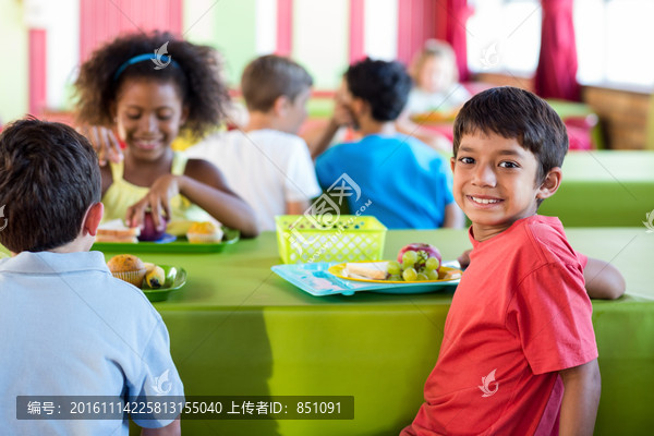 微笑的男学生和同学们在食堂吃饭