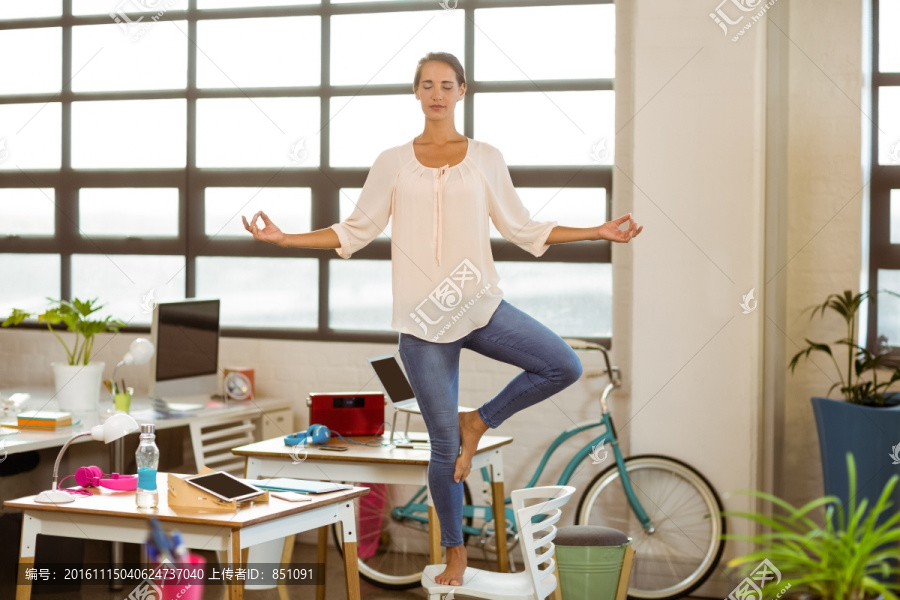 单脚站子椅子上练习瑜伽的女人