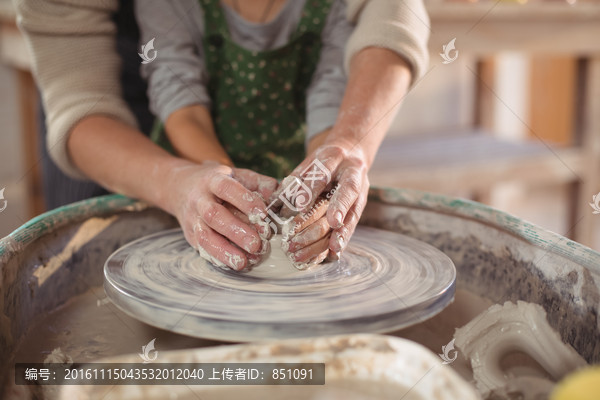 在协助女儿做陶器的母亲