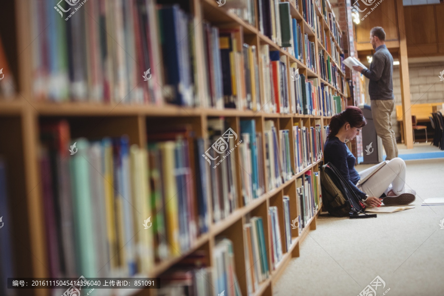 坐在图书馆地板上看书的大学生