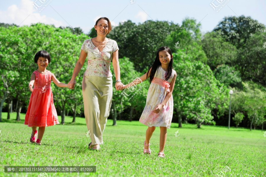 在公园里女人牵着女儿的手
