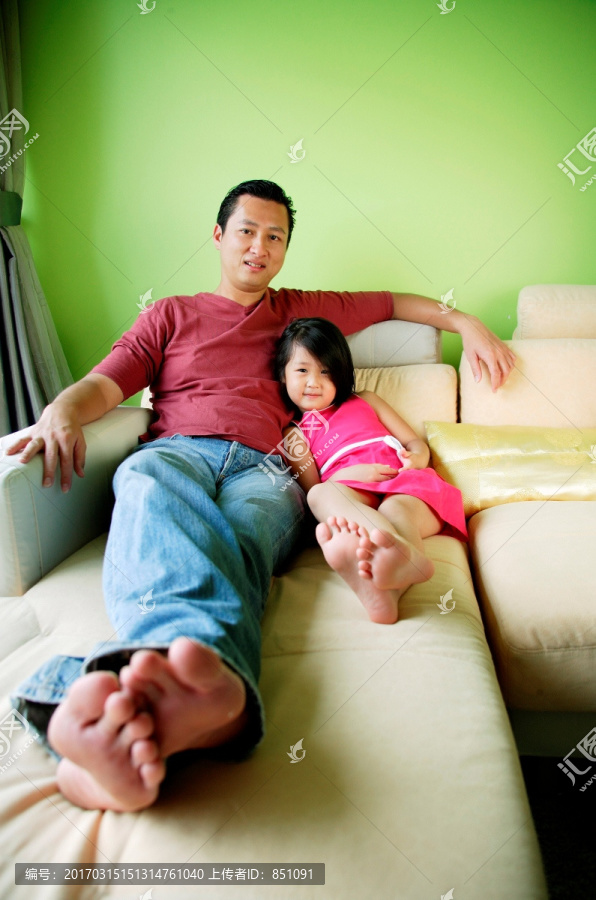 父亲和女儿躺在沙发上微笑