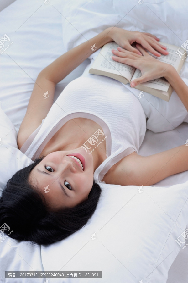 年轻女子躺在床上看书