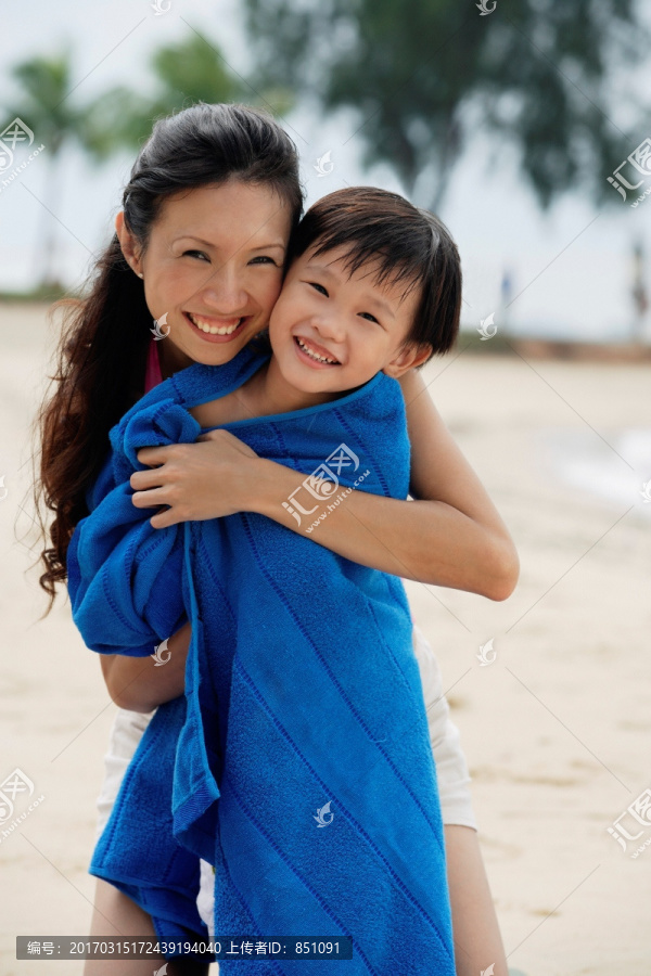 母亲抱着儿子在海滩上