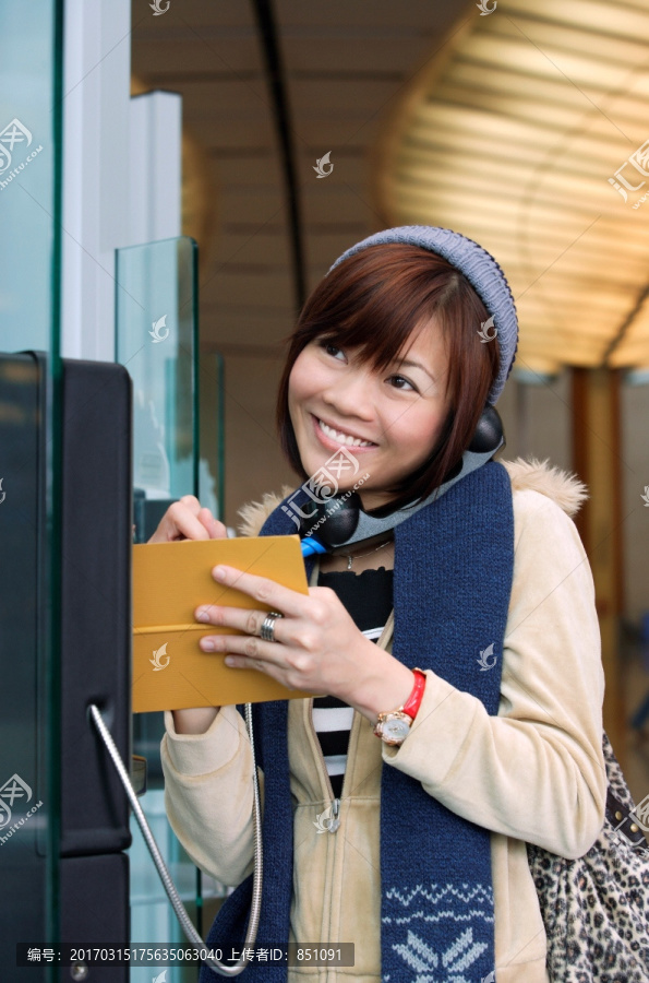 在机场公用电话的年轻女子