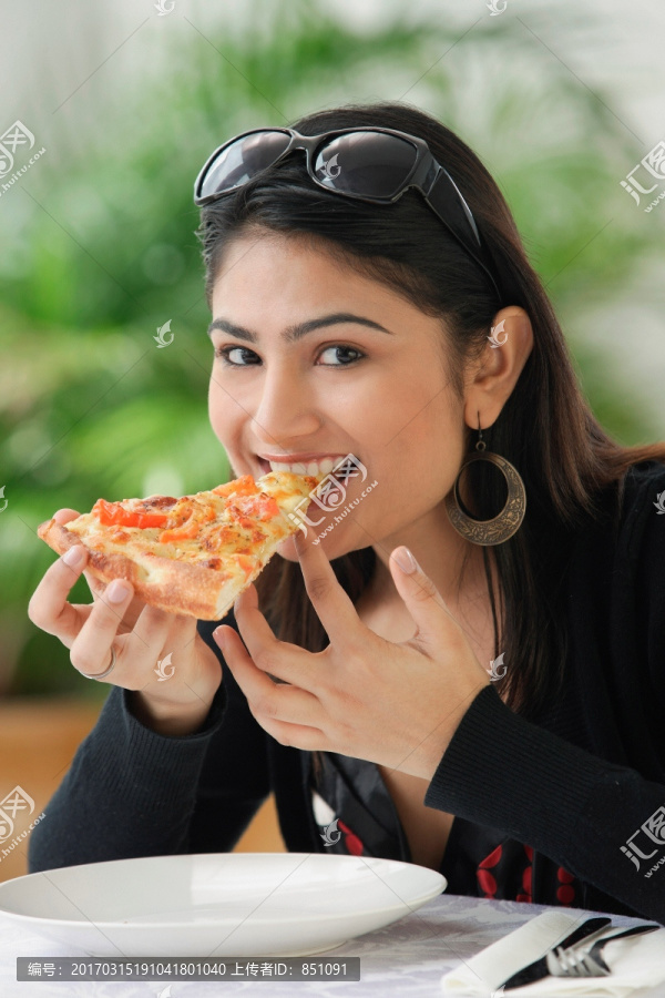 女人在吃一片比萨饼