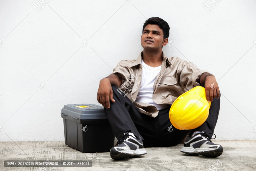 男子坐在地面举行建设帽