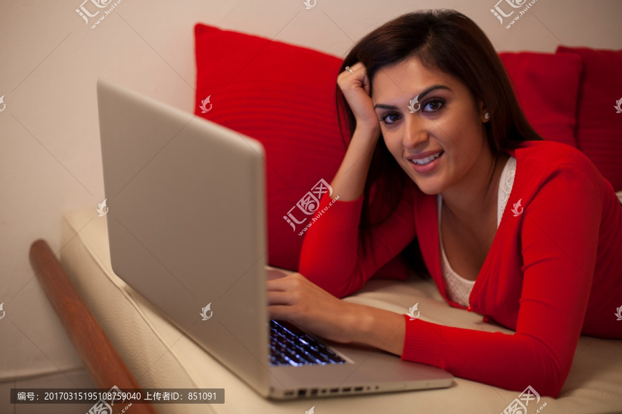 趴在沙发上使用笔记本电脑的女人