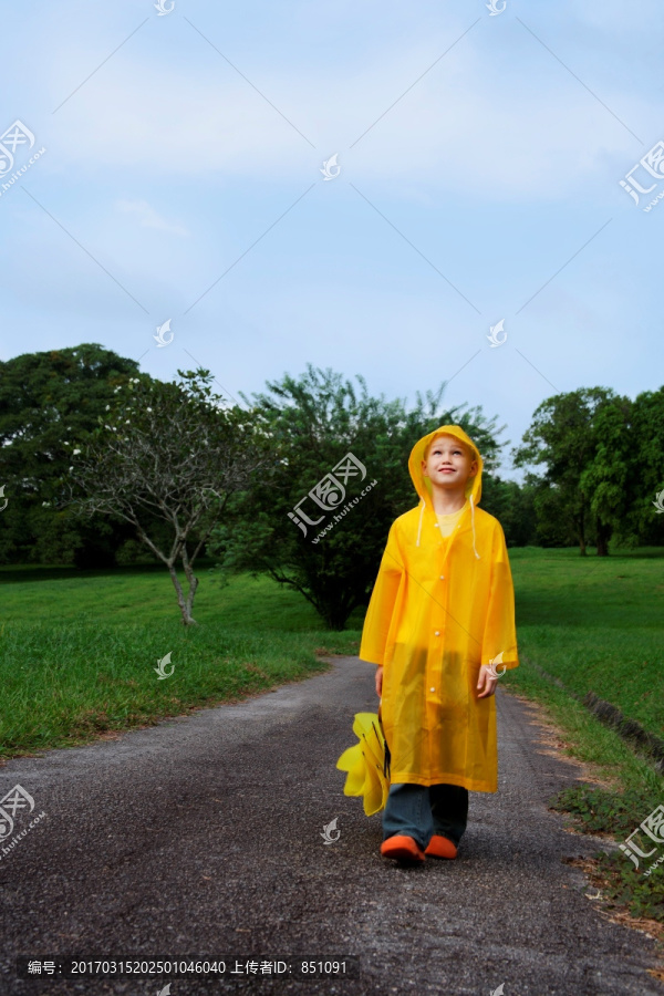 带着雨伞走在路上的男孩