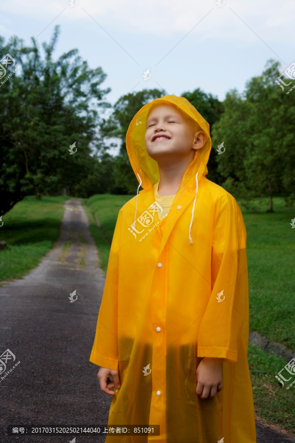 小男孩站在路上穿着雨衣