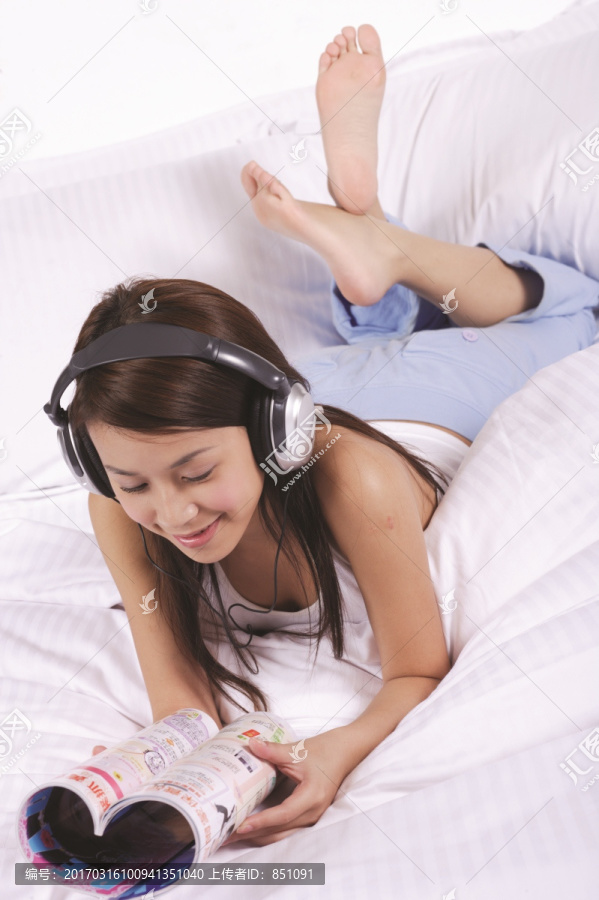 趴在床上看杂志听音乐的女人