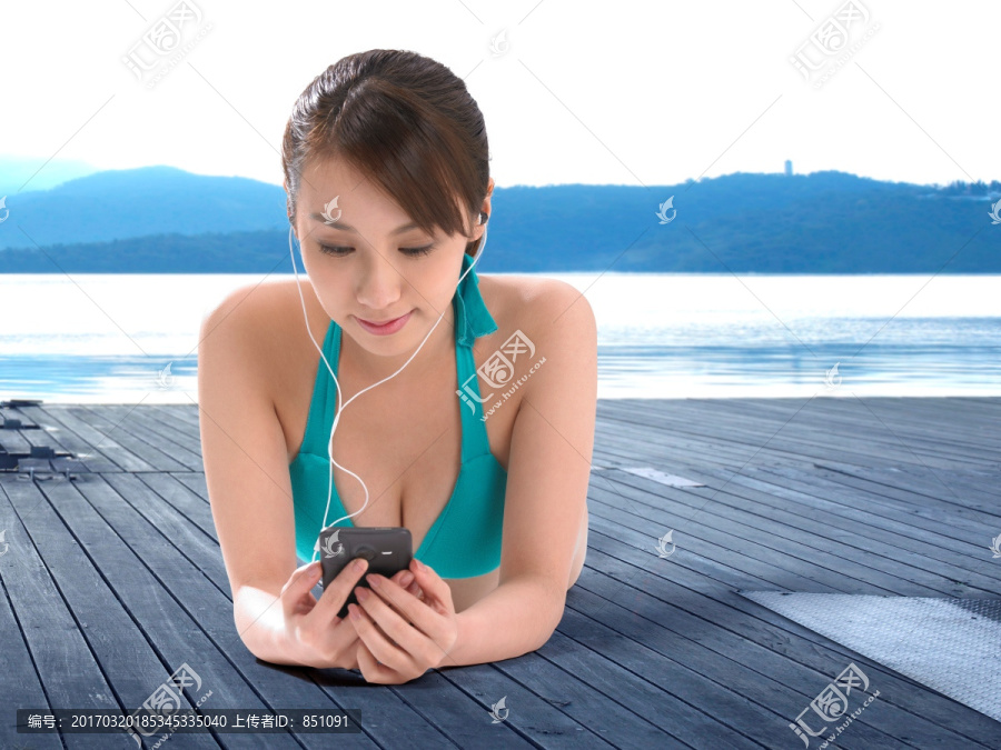 趴在木栈板上使用手机的女人