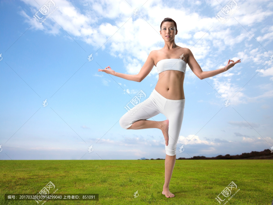 站在草坪上做瑜伽的年轻女人