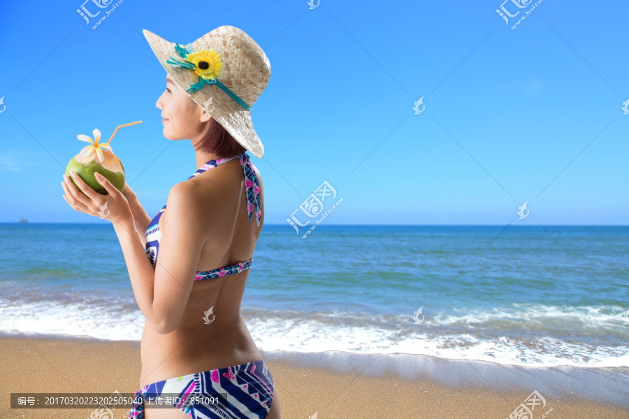 在海边喝椰汁的女人