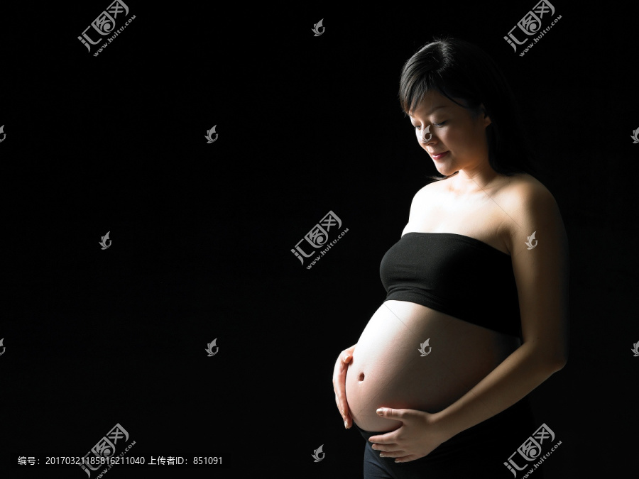 微笑的孕婦雙手放在肚子上