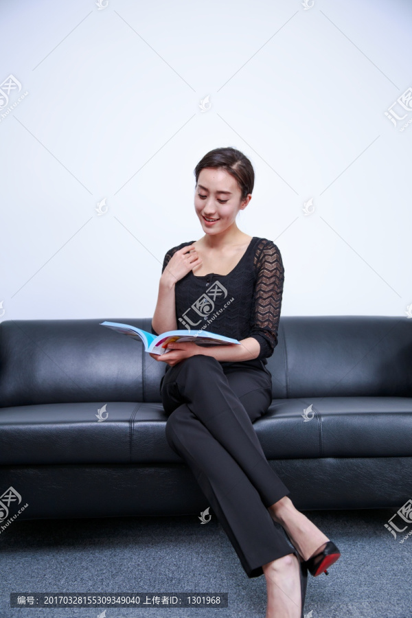坐在沙发上微笑着看书的女人