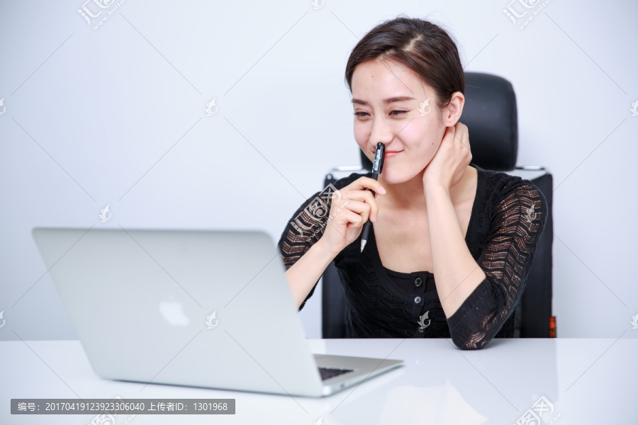 坐在办公椅上看着笔记本电脑的女人