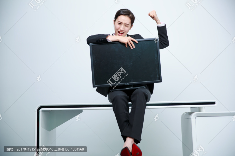 坐在办公桌上拿着电脑放在腿上的女人