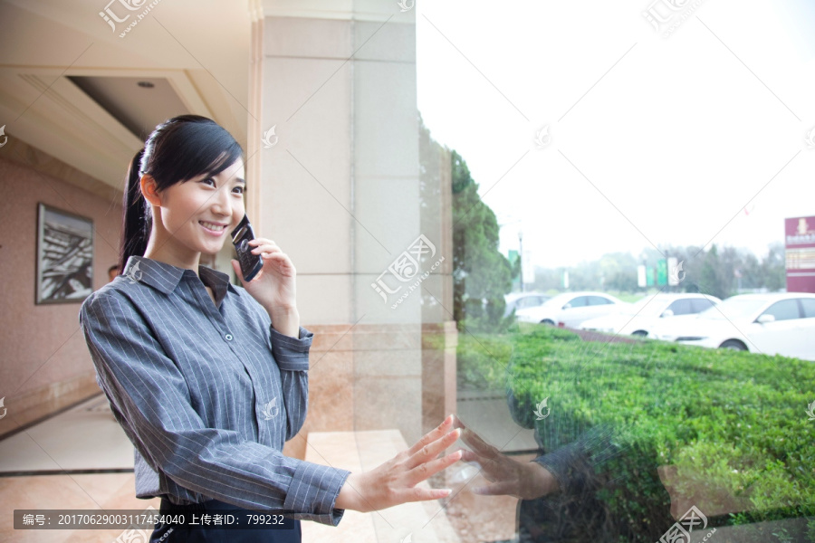 落地窗边打手机的年轻商务女士