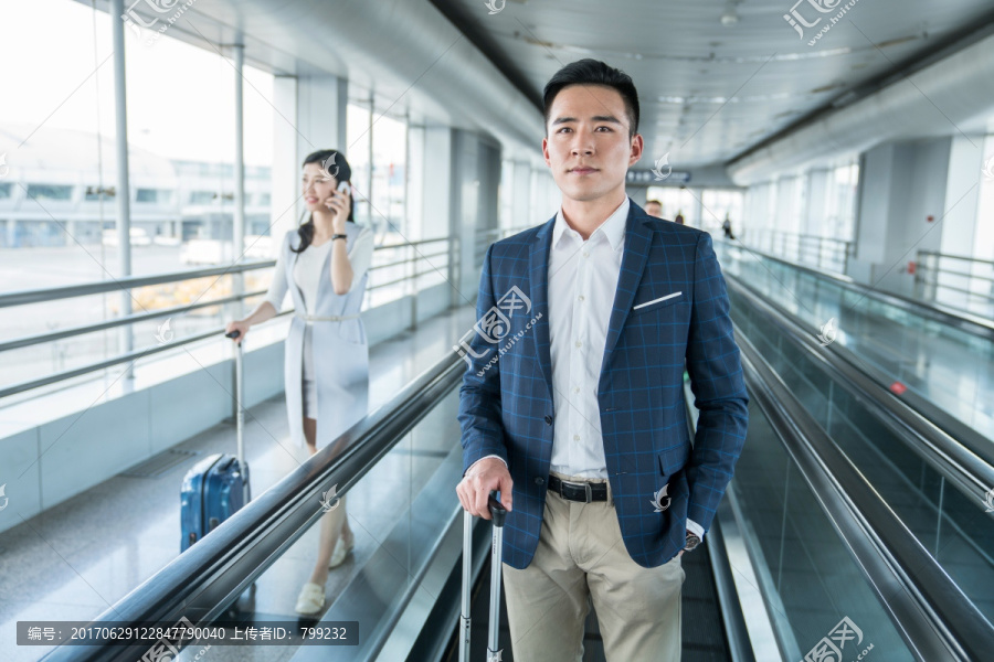 年轻商务人士在机场乘坐移动电梯
